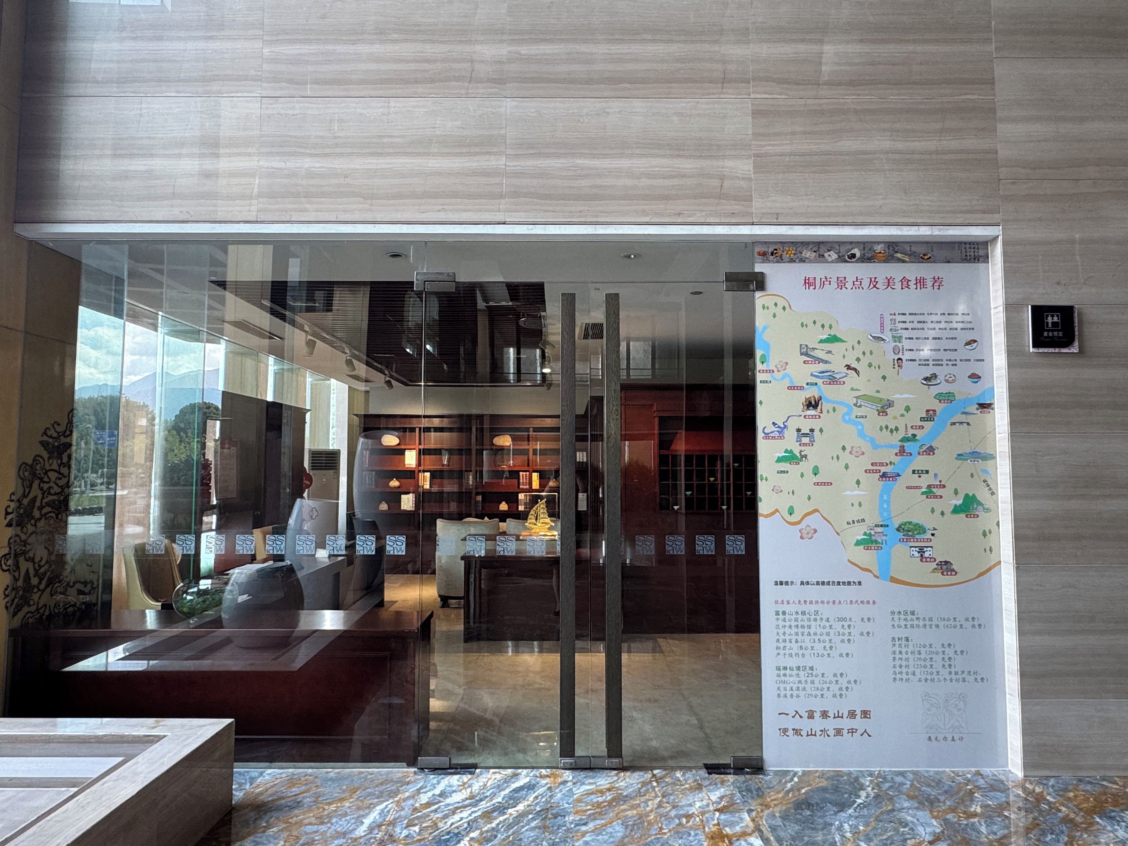 A hotel lobby with a reception desk, seating area, and a map on the wall.