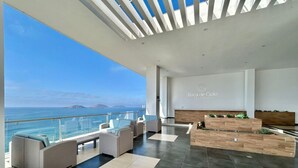 A modern lounge area with seating and a reception desk, overlooking a scenic ocean view. - Boca de cielo Apartments (Mazatlán)