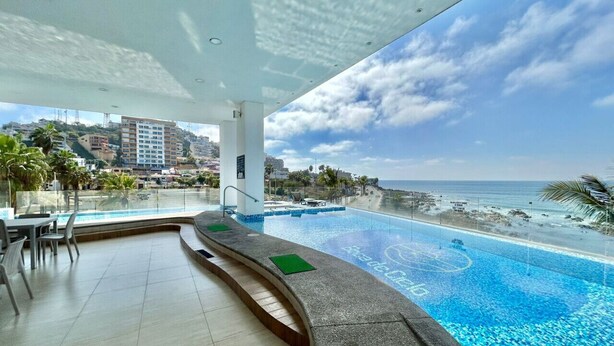 A hotel pool area with a view of the beach and cityscape. - Boca de cielo Apartments (Mazatlán)