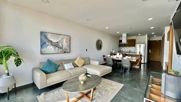 A modern living room with a sofa, coffee table, and dining area.