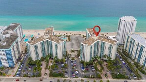 Ein Hochhaus-Hotel mit mehreren Stockwerken, einem zentralen Innenhof und Blick auf Strand und Meer.