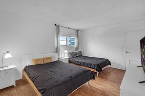 Une chambre moderne avec deux lits, une table de chevet, un bureau et une fenêtre avec des rideaux.
