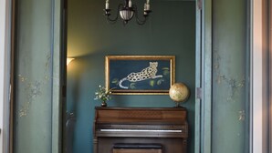 A room with a piano, a chessboard, and a globe on a table. - Historic Manor Overlooking Park (Bloomington)