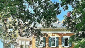 A two-story house with a front porch, a green door, and a number 210 sign above the door. - Historic Manor Overlooking Park (Bloomington)