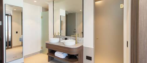 Un baño moderno con dos lavabos, un espejo grande y un mueble de tocador de madera.