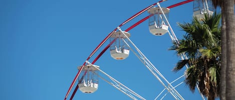A Ferris wheel with cabins against a clear blue sky.