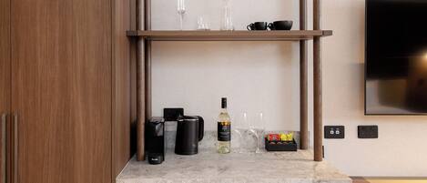 Una cocina moderna con armarios de madera, encimera de mármol, estante empotrado con utensilios de cocina y televisor de pantalla plana montado en la pared.