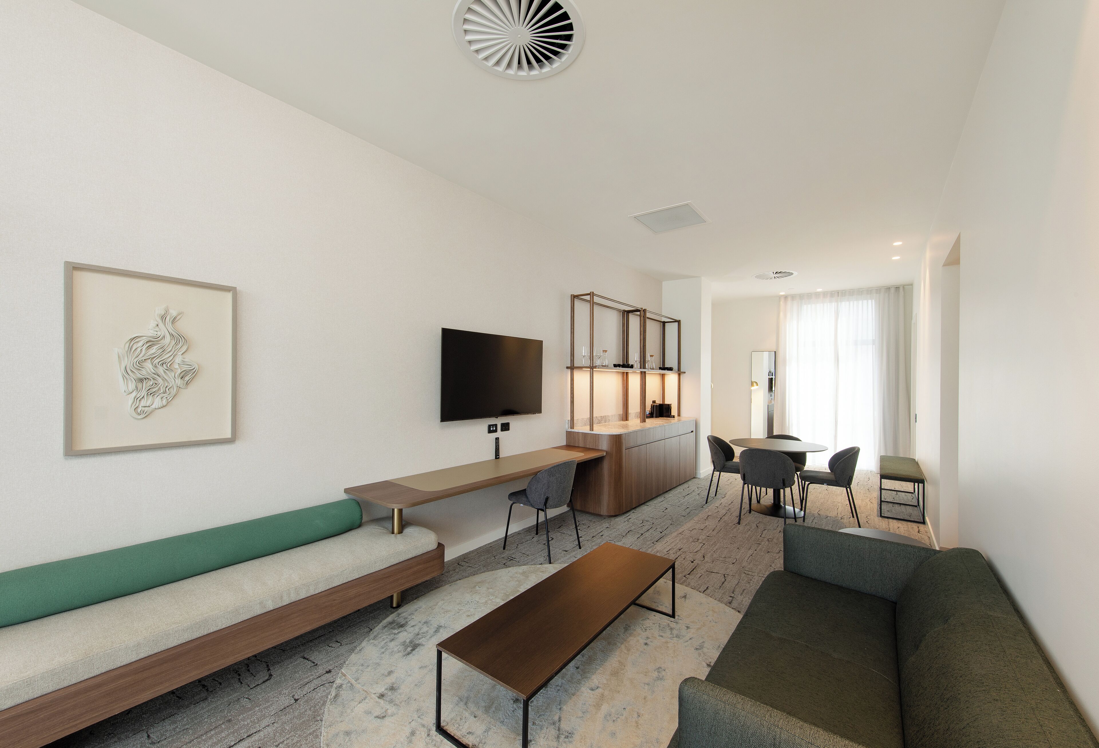 A modern living room with a sofa, a coffee table, a TV, and a dining area with chairs and a table.