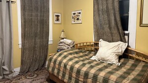 A bedroom with a bed, curtains, a lamp, and a framed picture on the wall. - Charming 2-bedroom apartment with wifi.   Three blocks to ferry.   (New Orleans)