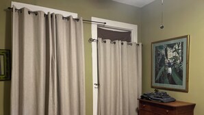 A room with beige curtains, a wooden dresser, and a framed picture on the wall. - Charming 2-bedroom apartment with wifi.   Three blocks to ferry.   (New Orleans)