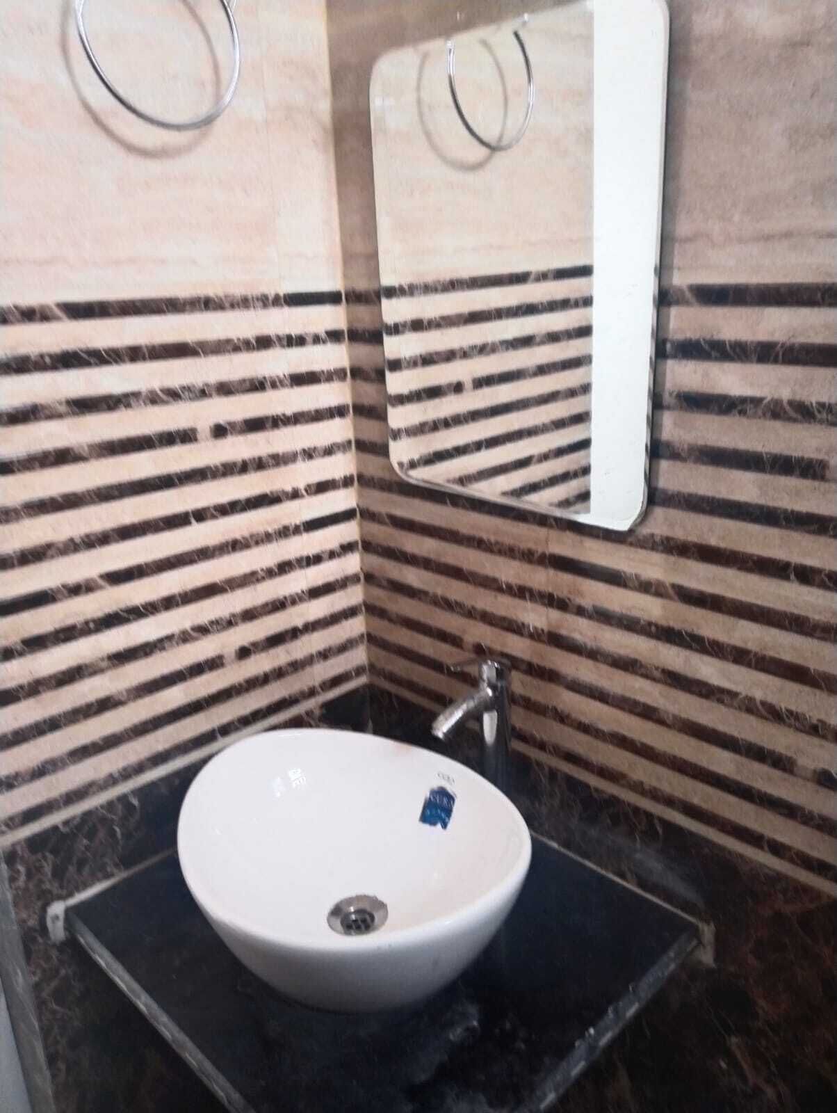 Un baño con un lavabo blanco, un espejo y paredes con azulejos a rayas.