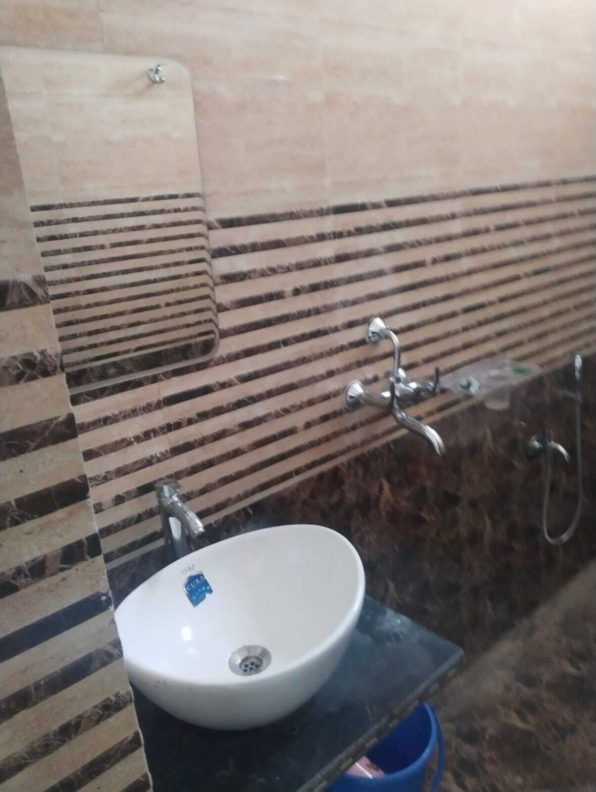 Un baño con lavamanos blanco, un espejo y zona de ducha.
