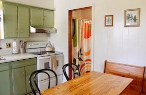 A kitchen with green cabinets, a stove, and a dining table with chairs.
