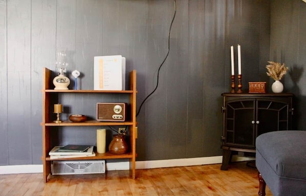 Una habitación con una estantería de madera, una radio antigua, una vela y un pequeño aparador con velas.