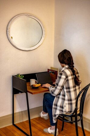 Una persona usando una computadora portátil en un escritorio, con una taza, un plato de galletas y una planta cerca.