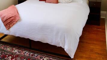 A neatly arranged bedroom with a bed, bedside tables, a mirror, and a patterned rug.