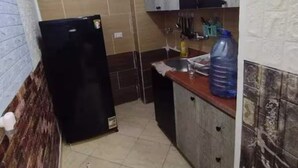 A compact kitchen with a black refrigerator, a sink, and a large water dispenser on the countertop. - Sekhmatone 1-bedroom apartment (Luxor)