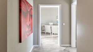 A hallway with a modern interior, leading to a dining area with a white table and chairs. - Seaside 74 - Seaside 74, tastefully furnished, bright 2-room apartment with (Timmendorfer Strand)
