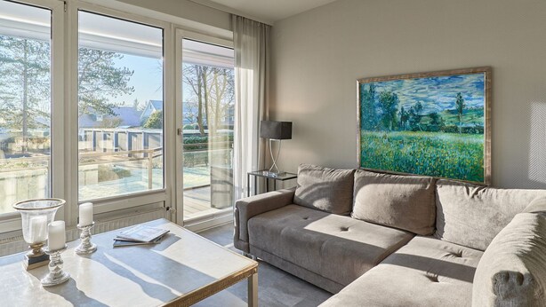 A modern living room with a sofa, a coffee table, and a painting on the wall. - Seaside 74 - Seaside 74, tastefully furnished, bright 2-room apartment with (Timmendorfer Strand)