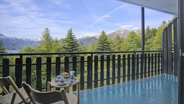A balcony with a view of mountains, a table with dishes, and chairs. - Appartamento Bellevue Richardette with Terrace, Sauze d'Oulx, Italy (Sauze d'Oulx)