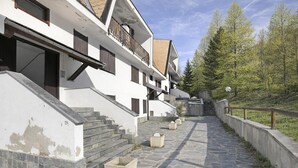 A multi-story building with a stone staircase leading to a wooden door, surrounded by trees and a clear sky. - Appartamento Bellevue Richardette with Terrace, Sauze d'Oulx, Italy (Sauze d'Oulx)