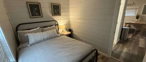 A bedroom with a bed, bedside tables, and framed pictures on the wall.