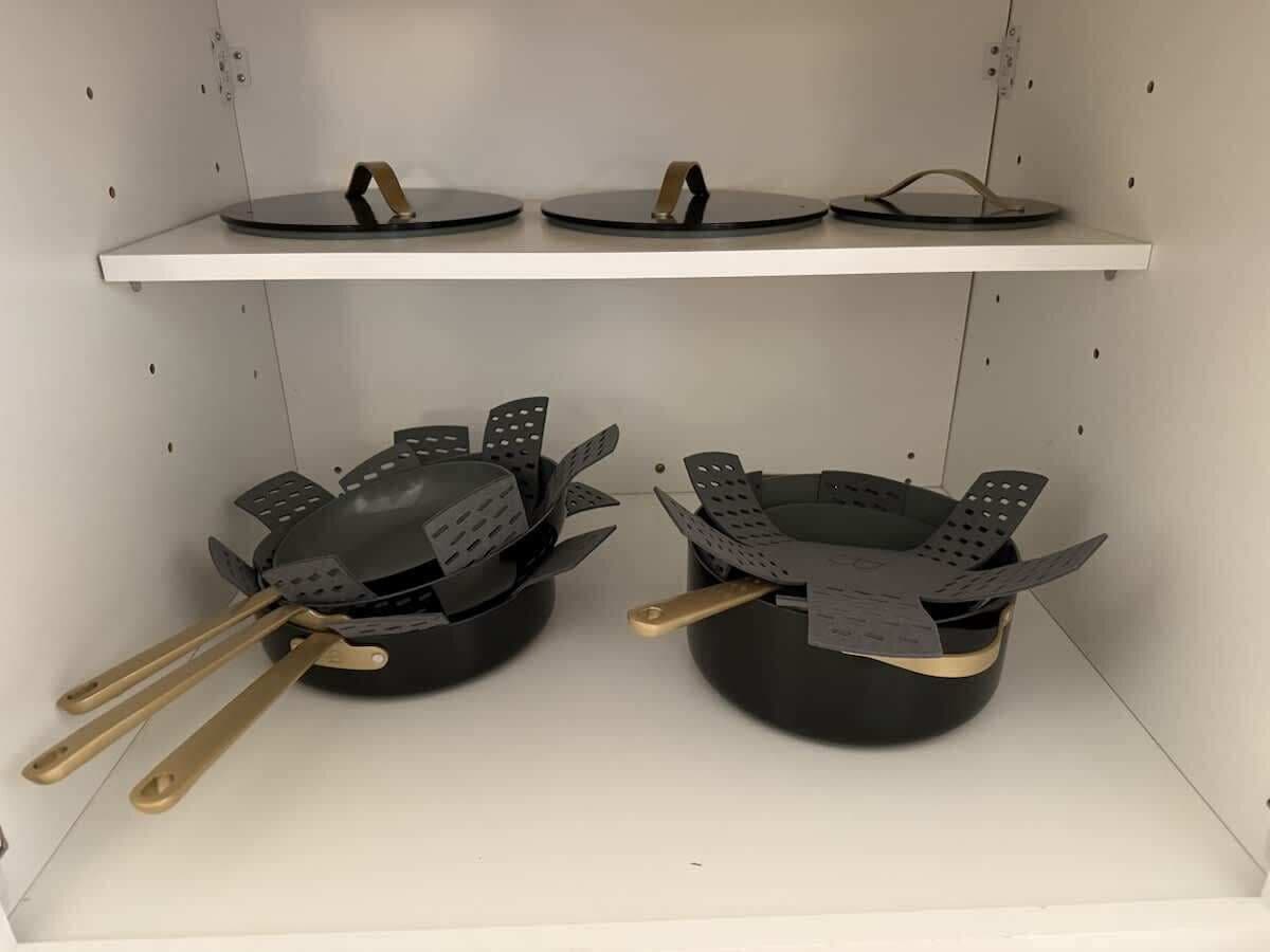 A kitchen with two black pots on the counter, each with a pair of golden handles.