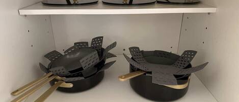 A kitchen with two black pots on the counter, each with a pair of golden handles.