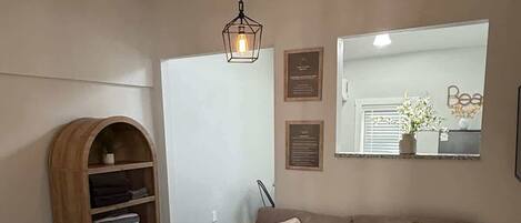 Une chambre à coucher comprenant un lit, un canapé, une armoire en bois, un luminaire suspendu et une fenêtre avec des stores.