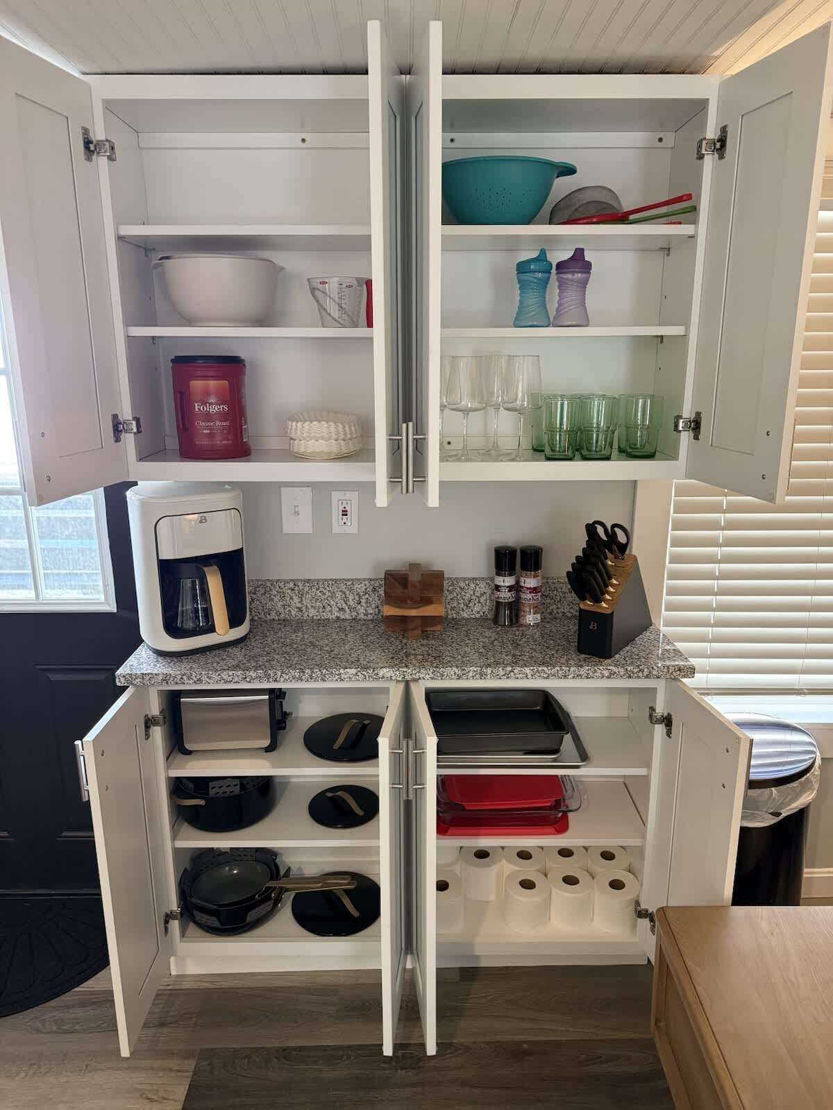 A compact kitchen with a coffee maker, storage shelves, and a countertop.