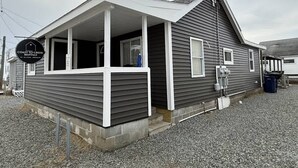 Un bâtiment d’un seul étage doté d’un porche, d’une enseigne indiquant qu’il propose des logements à la location et d’une allée gravillonnée.