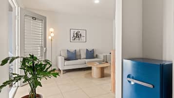 A modern living room with a sofa, a coffee table, a blue cabinet, and a potted plant.