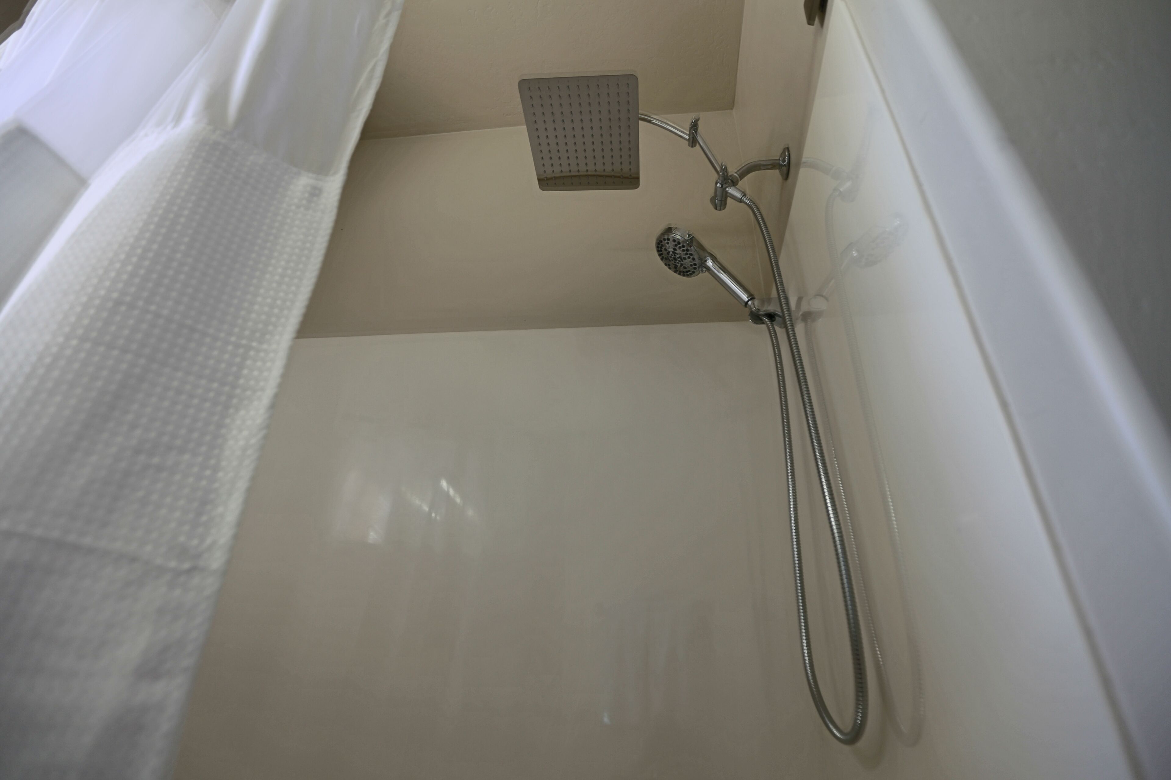 Une salle de bain équipée d’une douche, d’un pommeau de douche amovible et d’un robinet mural.