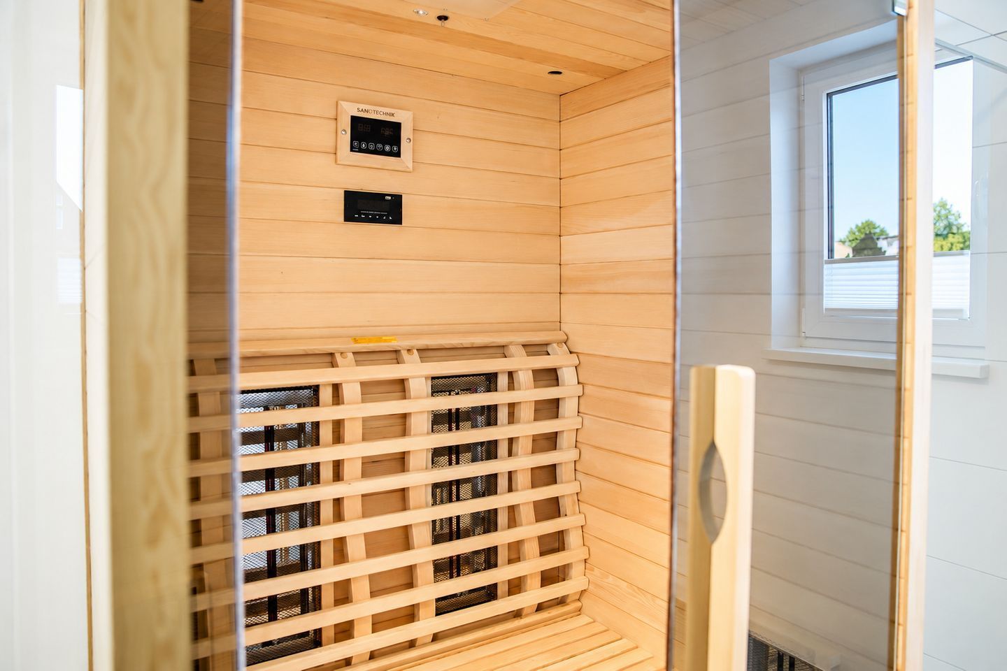 Una sauna con interior de madera, un panel de control y una ventana.