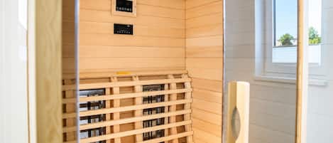 Una sauna con interior de madera, un panel de control y una ventana.
