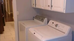A laundry area with two white washing machines and cabinets above.
