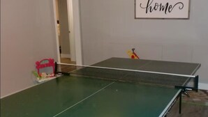 A ping pong table in a room with a 'home' sign on the wall.