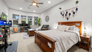 A bedroom with a wooden bed, a desk, a chair, a TV, and exercise equipment. - Tranquil Retreat: Pool, Spa, Firepit, Peloton, WFH (Orangevale)