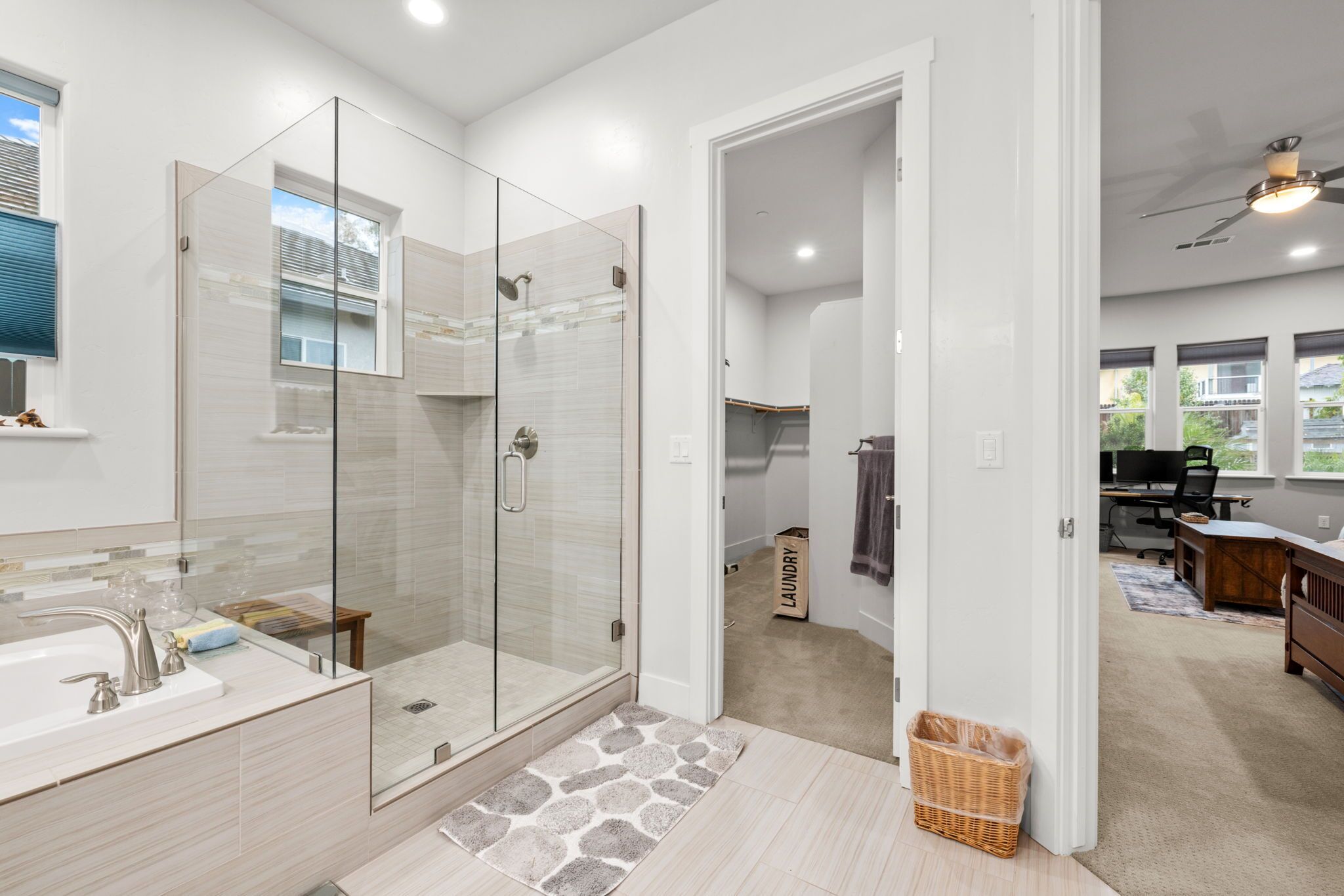 Une salle de bain moderne avec une douche à parois de verre, un grand lavabo et un panier à linge visible.