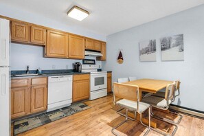 Una cocina compacta con armarios de madera, una estufa y un comedor con mesa y sillas.