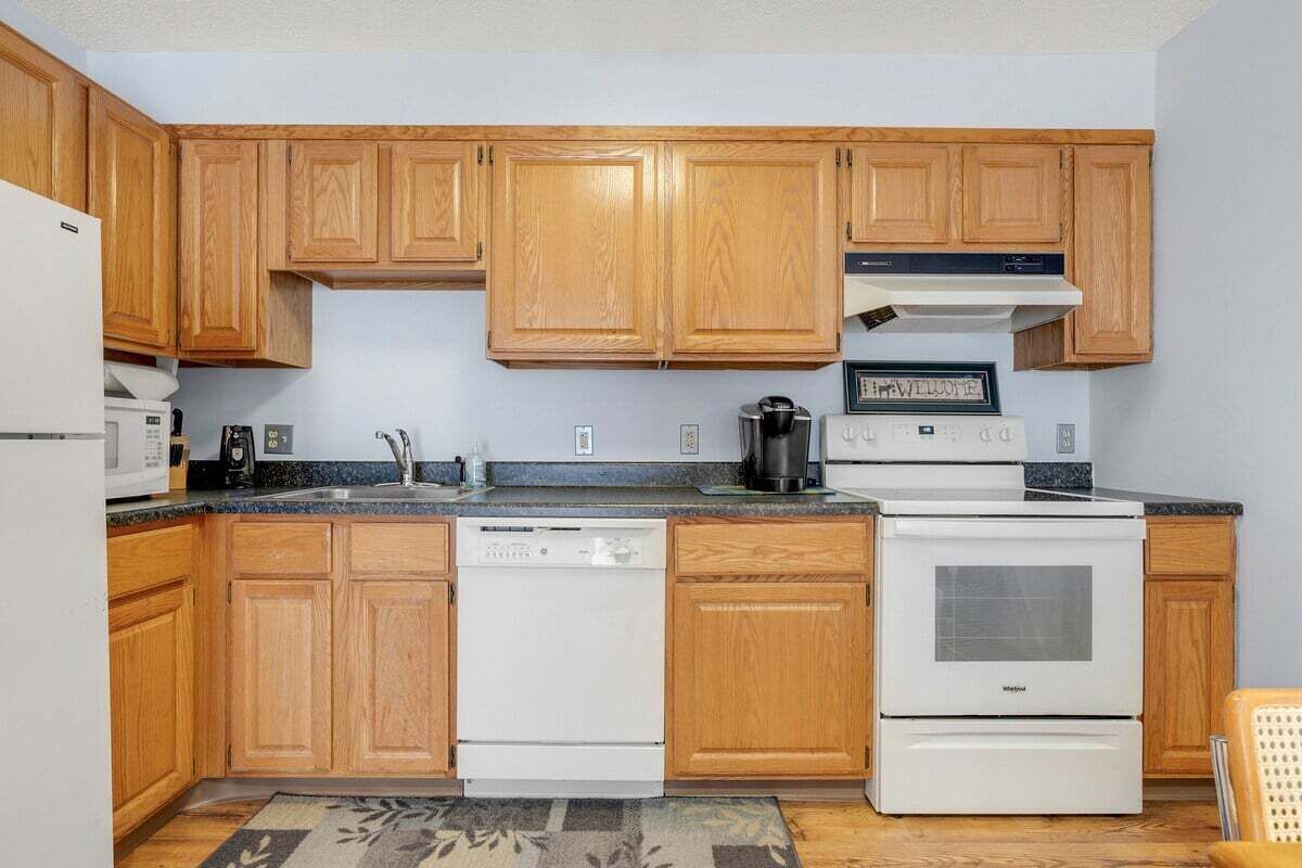 A kitchen with wooden cabinets, a dishwasher, a stove, and a microwave.