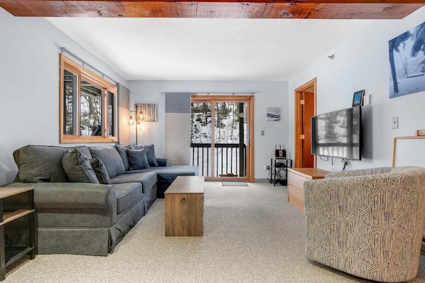 A modern living room with a sofa, coffee table, and patterned ottoman.
