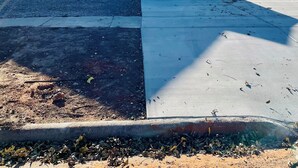 Edificio de una sola planta con puerta principal, un pequeño porche y un camino de acceso a un estacionamiento.