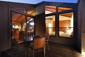 Ein gemütliches Blockhaus mit Essbereich und einem Schlafzimmer, die durch große Fenster sichtbar sind.