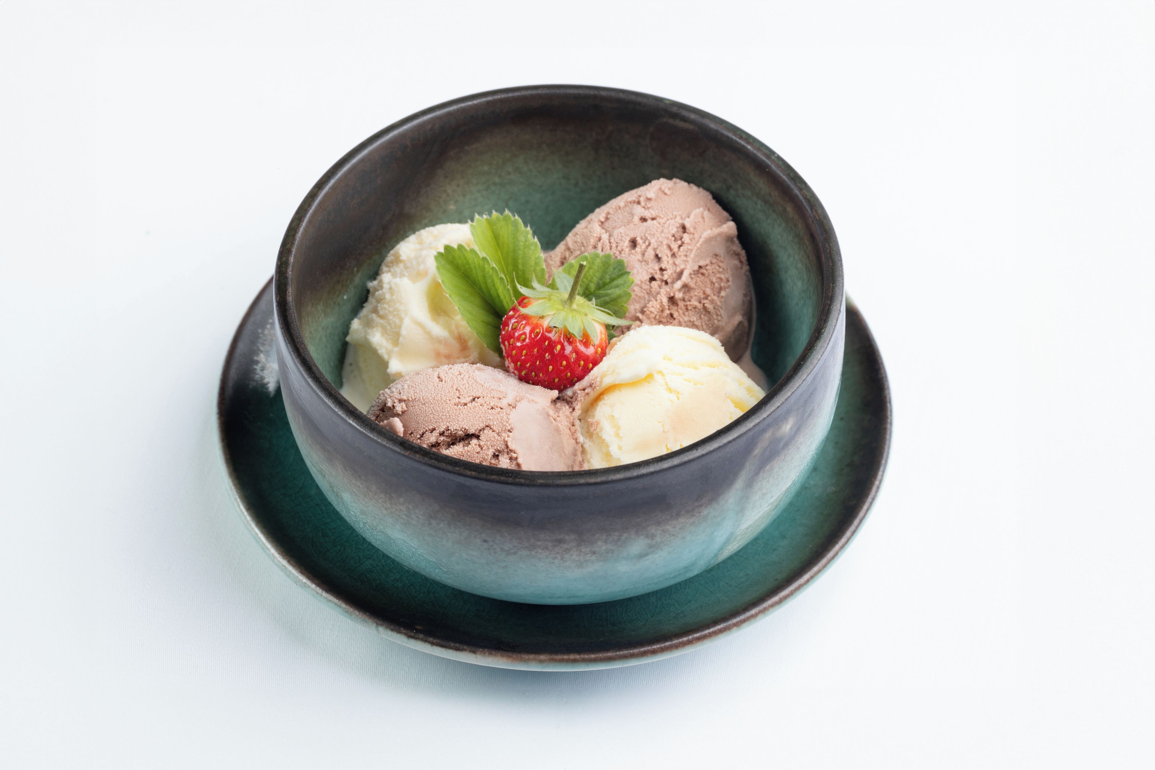 A bowl of ice cream with a strawberry garnish.