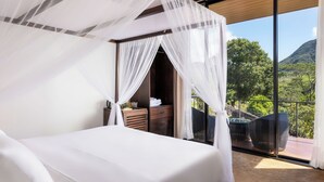 Une chambre à coucher avec un lit à baldaquin, une commode en bois et une vue sur une piscine et des montagnes.