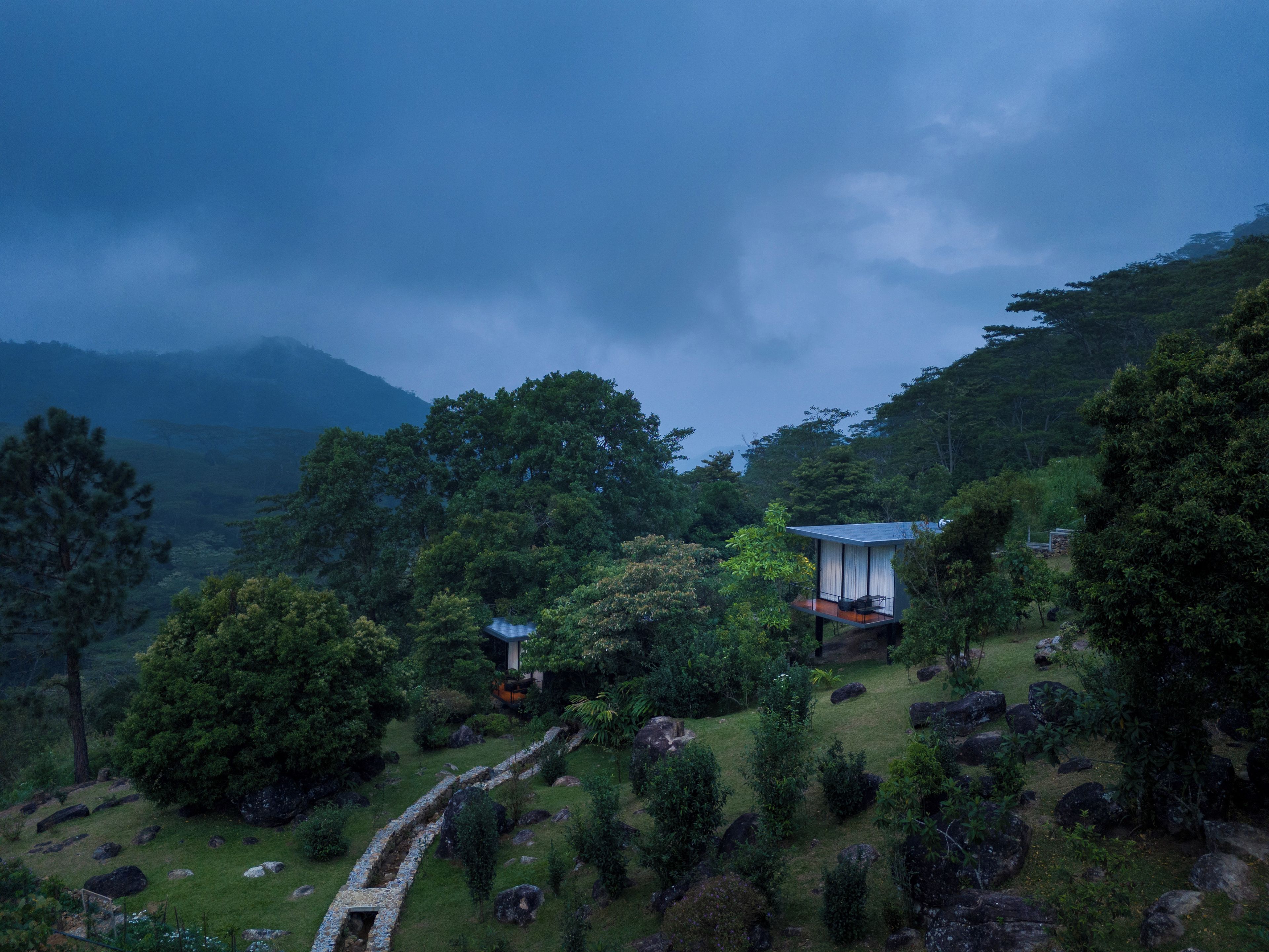Een traditioneel Japans huis met rieten dak, omgeven door weelderige begroeiing en een pad van stenen.