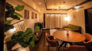 A modern dining area with a wooden table and chairs, a green sofa, and a large plant. - Sunmallcrest306 (Tokyo)