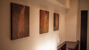 A hallway with three artworks on the wall and a dark wooden bench. - Sunmallcrest306 (Tokyo)