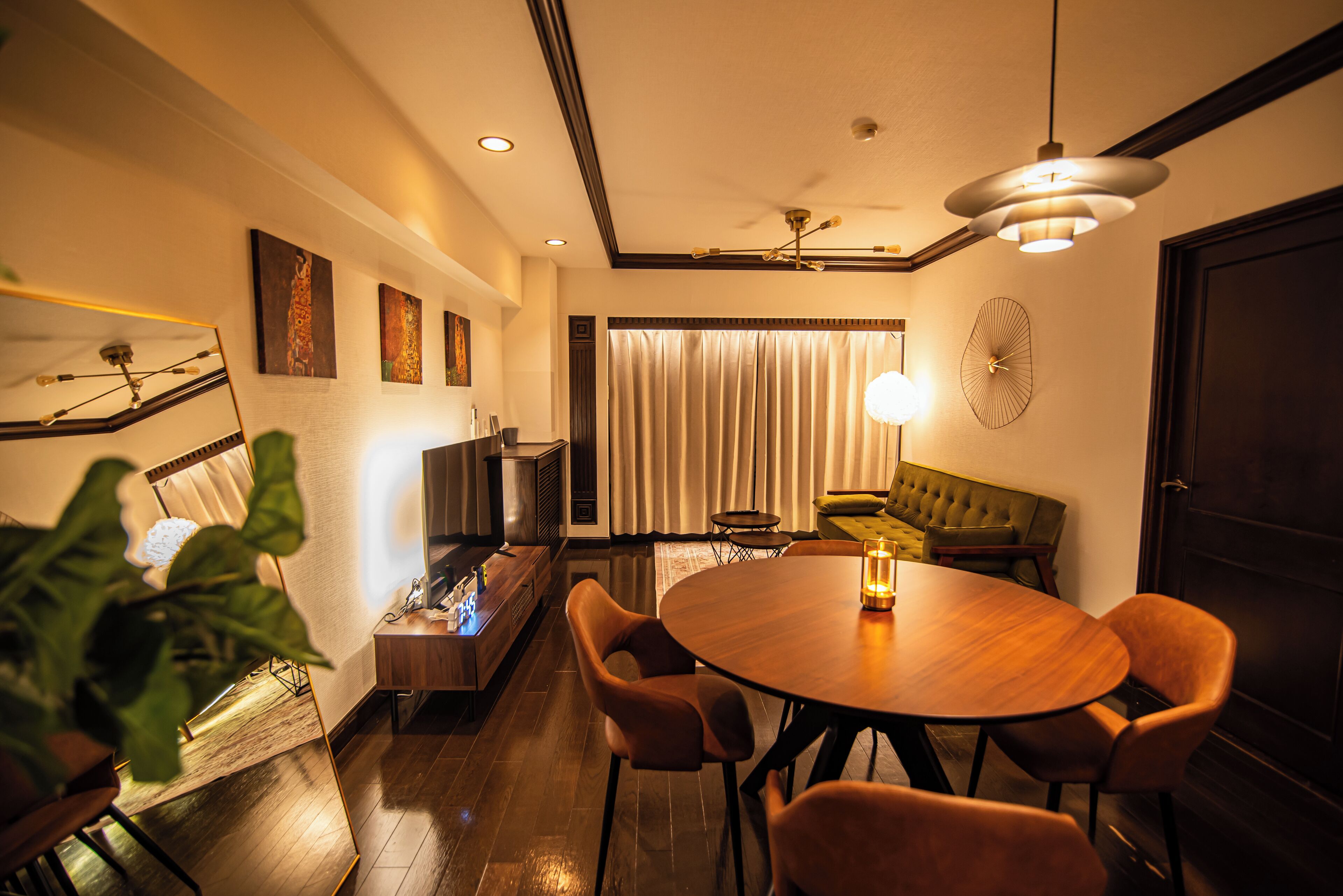 Un comedor moderno con una mesa redonda de madera, sillas acolchadas y un sofá verde.